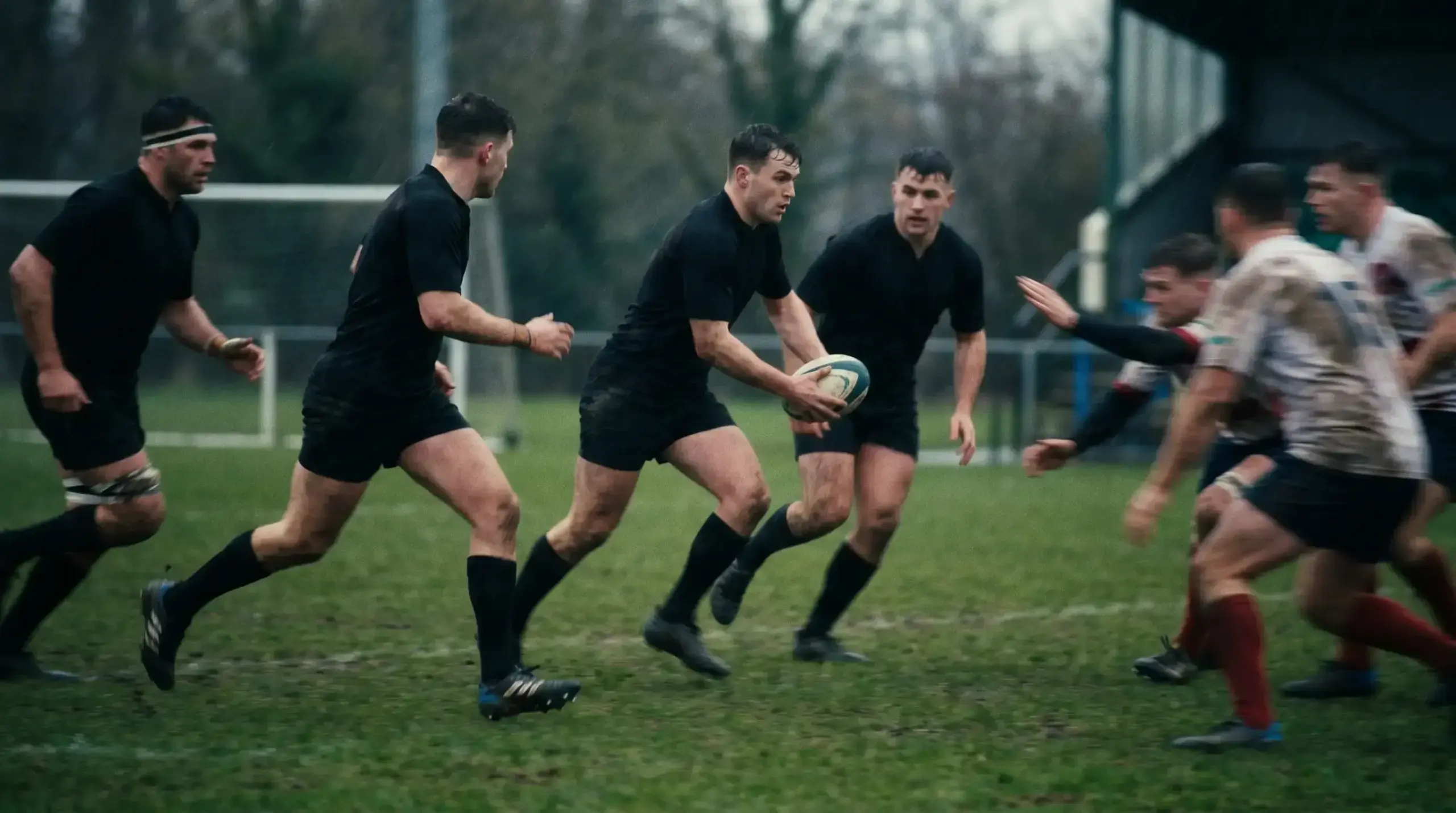 Rugby back line running an attacking pattern across a pitch