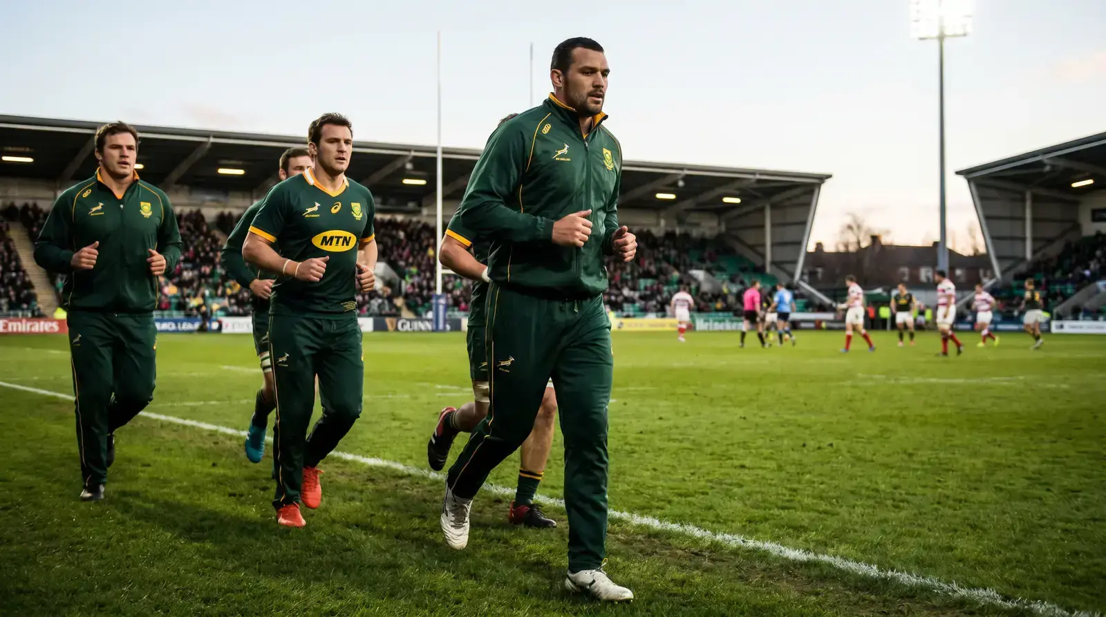 Rugby substitutes warming up on a touchline late in a match