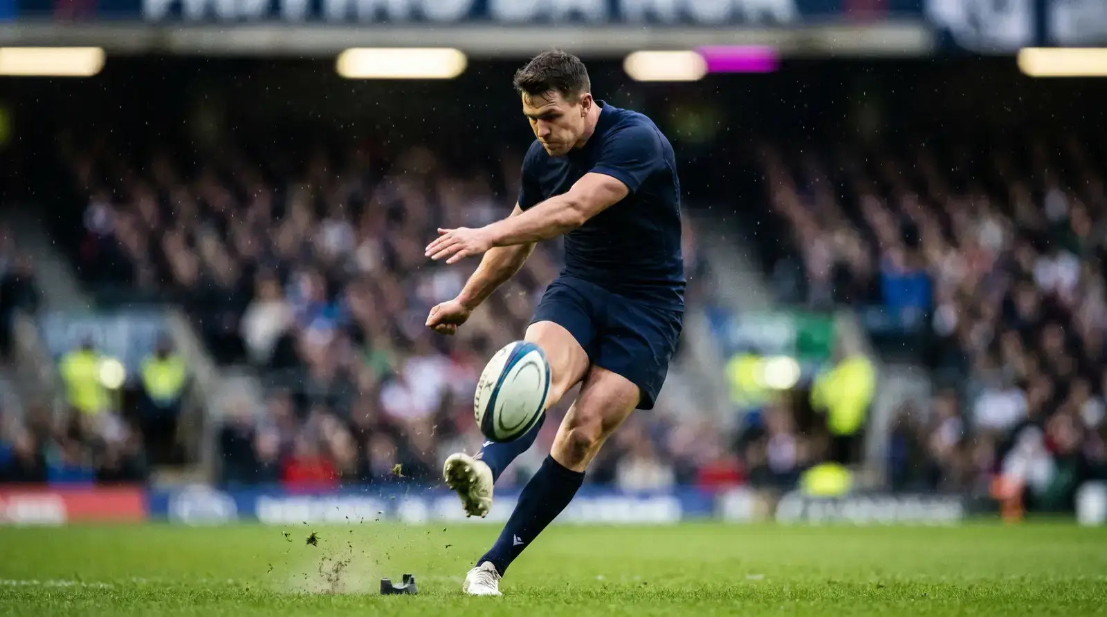 Rugby fly-half striking a place kick on a sunlit pitch
