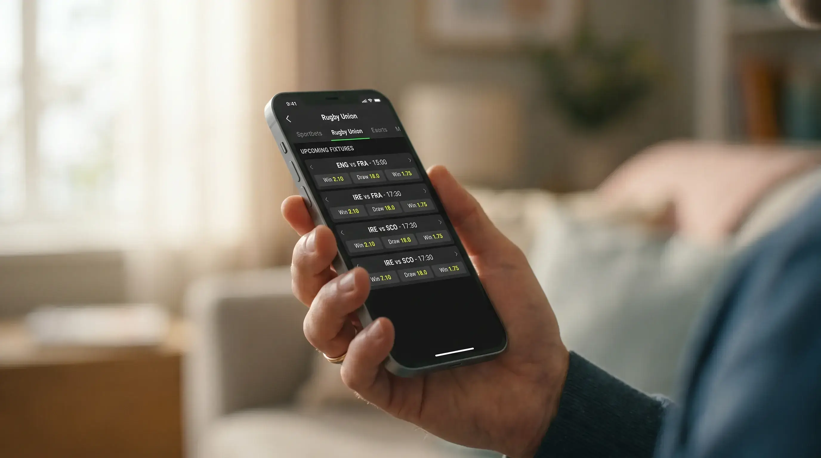 Close-up of a mobile phone screen displaying a UK-licensed sportsbook's homepage with rugby markets